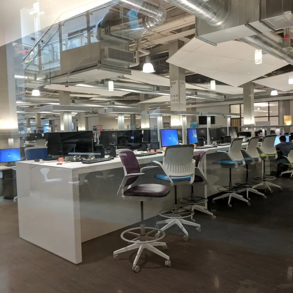 Rows of desktop computers and office chairs in a college media center.