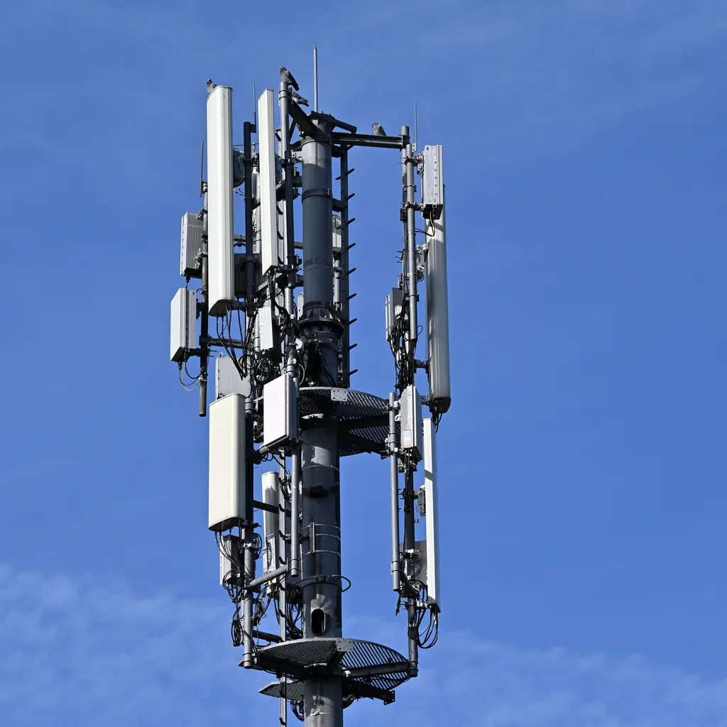 Panel antennas and cables surround the upper section of a cell tower.
