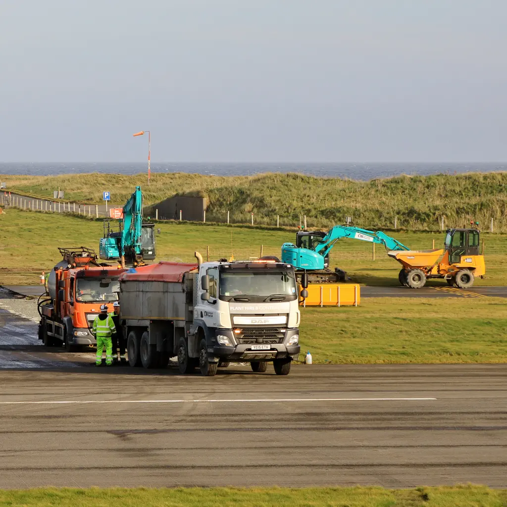Resurfacing equipment and a work truck on an airport runway.
