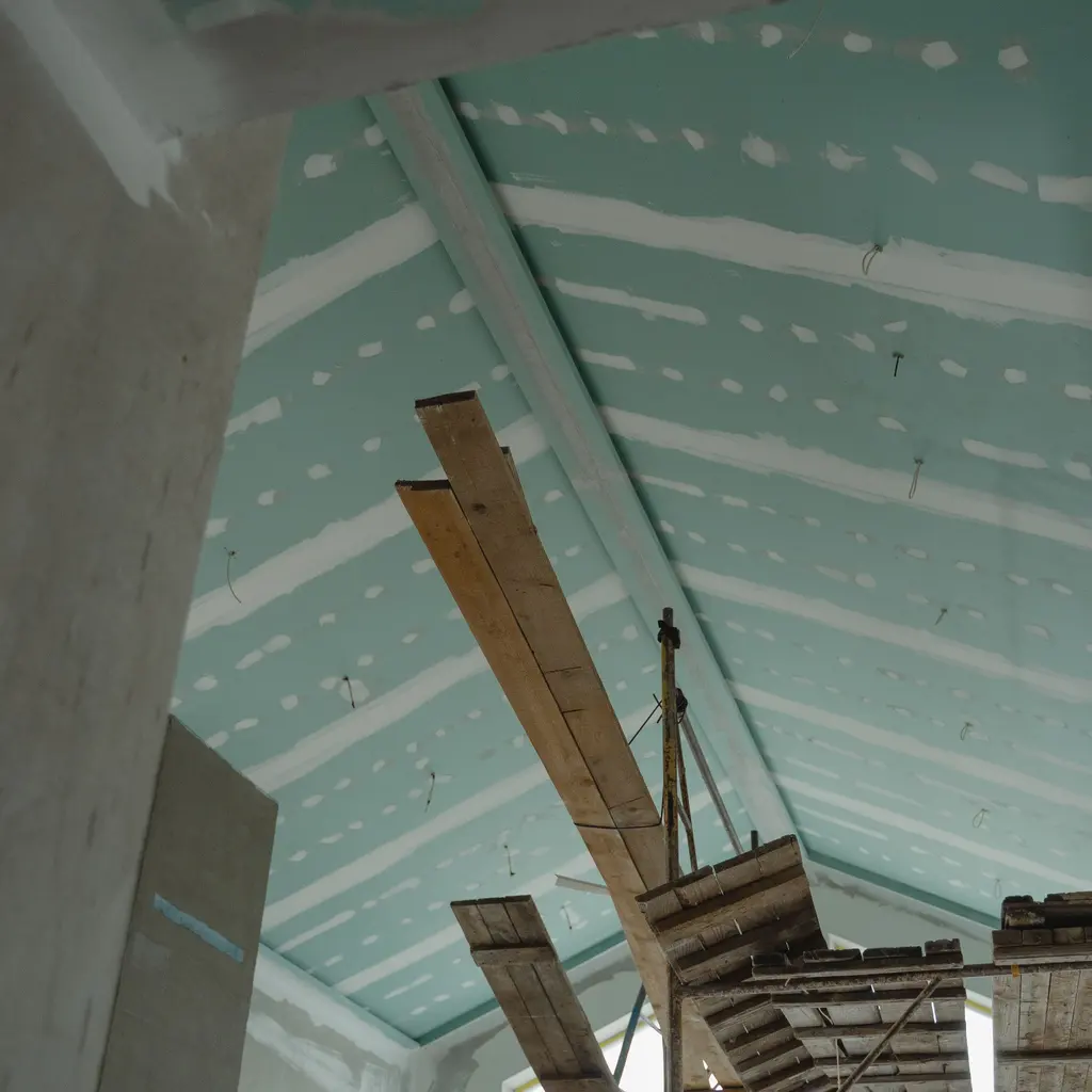 Suspended ceiling boards and temporary scaffold platforms fill an interior construction space.