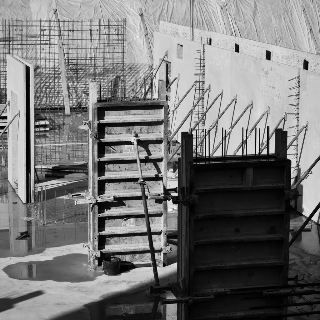 Reusable concrete wall form panels stand beside reinforcement at an active building site.