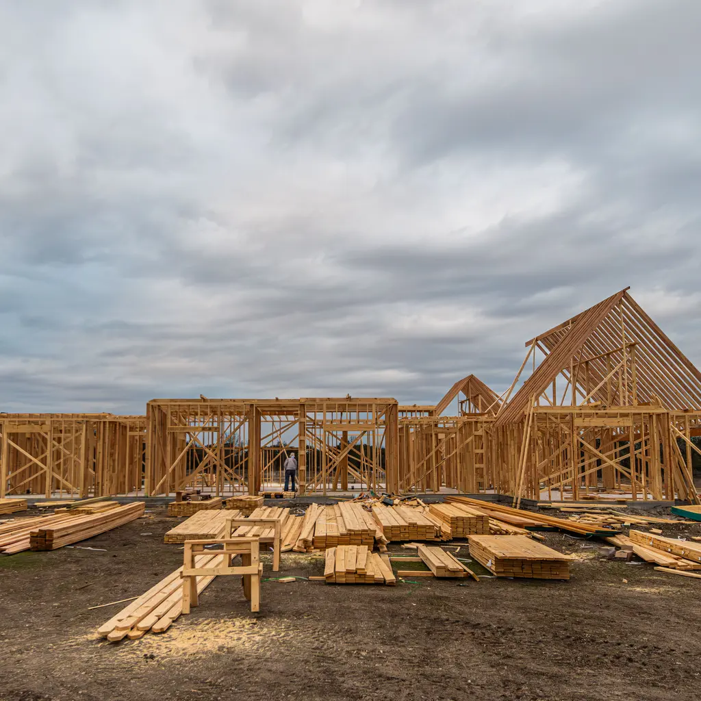 Timber walls and pitched roof framing form an individual house under construction.