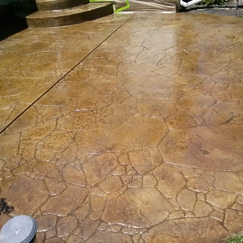 Stamped concrete paving has a textured stone-like pattern and warm brown decorative color staining.
