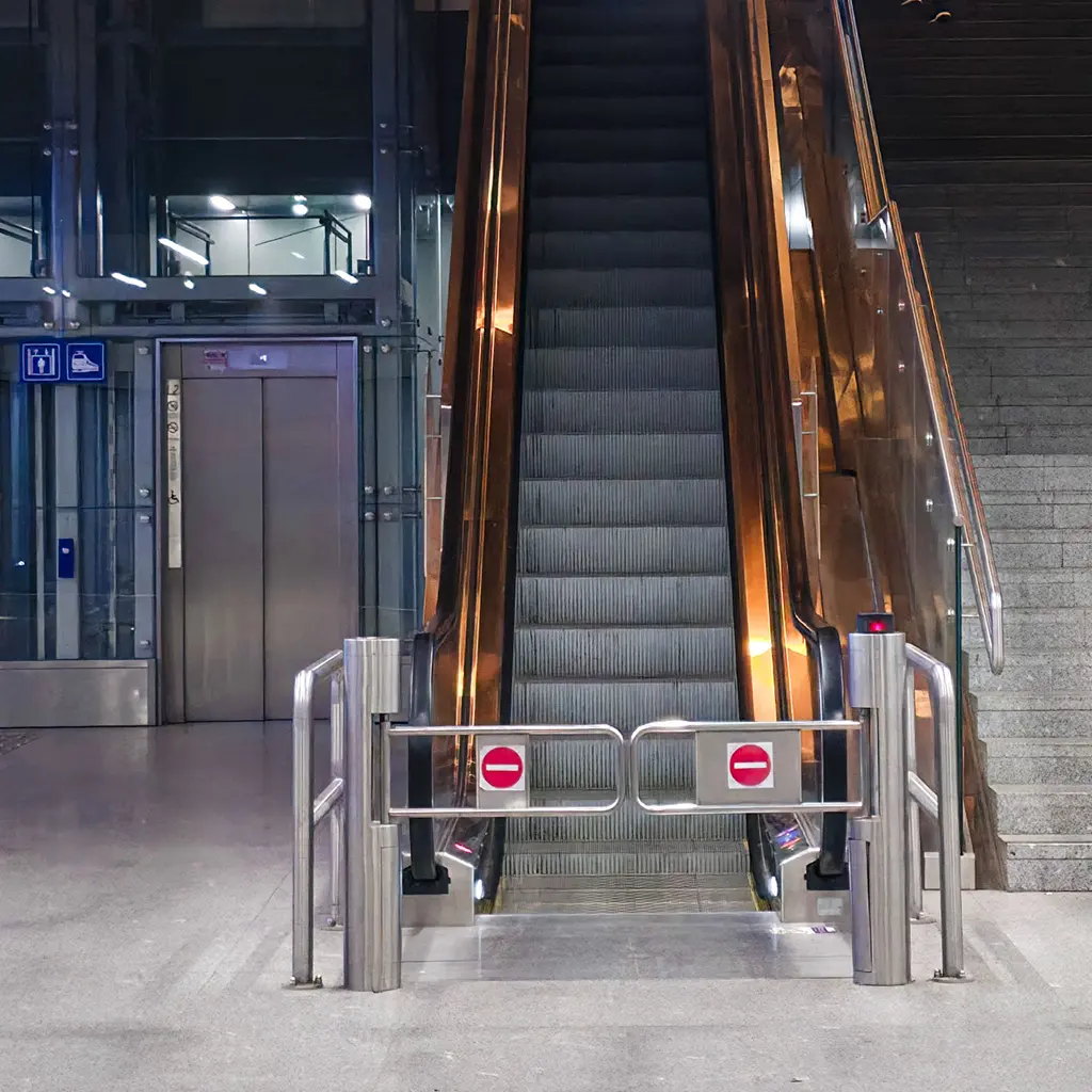 An indoor escalator beside glass elevator equipment in a modern public circulation area.