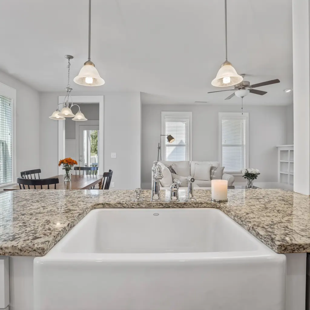 A fitted speckled granite kitchen countertop surrounding a white apron-front sink in a finished interior.