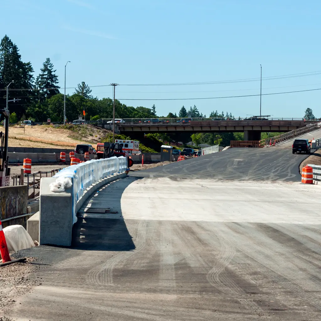 New metal highway guardrails line the approach to a road bridge.