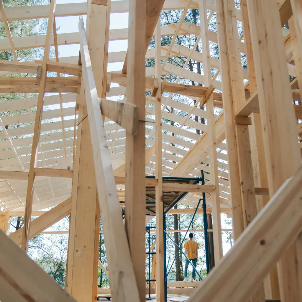 Exposed timber studs, rafters and temporary scaffolding inside a house under construction.
