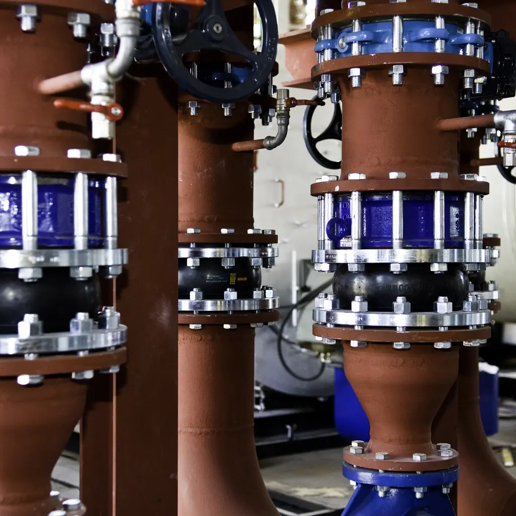 Large pipework, isolation valves and flexible joints inside a central heating plant.