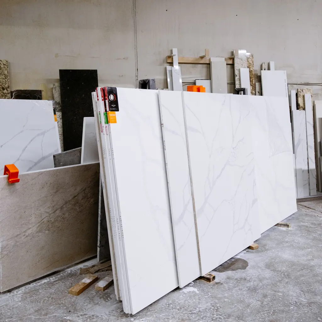Large white veined marble and other stone slabs stored upright in a stone-fabrication workshop.
