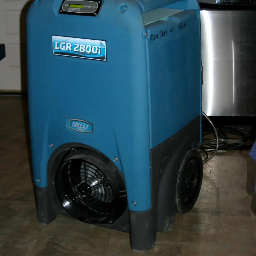 Portable commercial dehumidifier with a large fan housing standing on an interior floor.