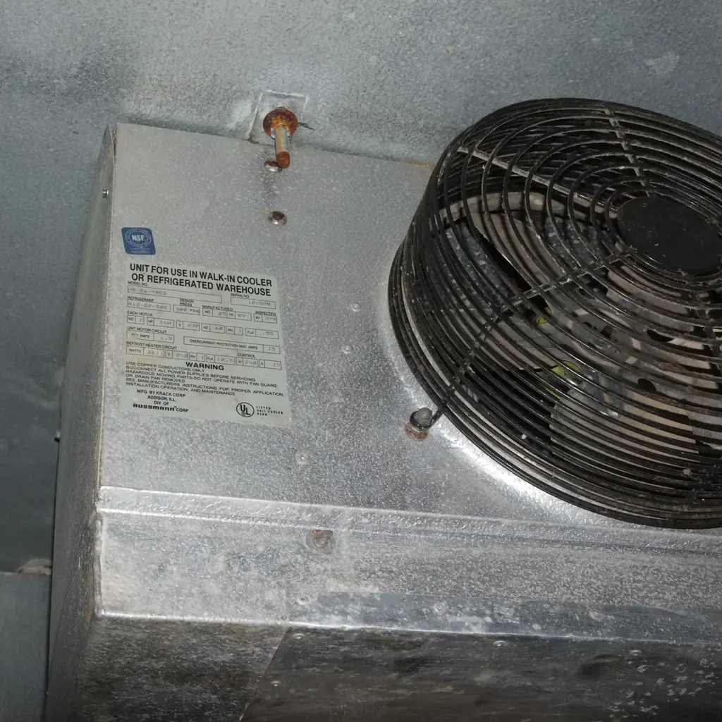 Metal refrigeration evaporator and fan mounted inside a walk-in cooler.