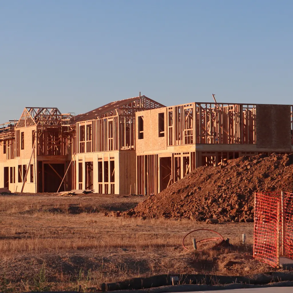 Multiple new homes in different framing stages on graded subdivision lots.