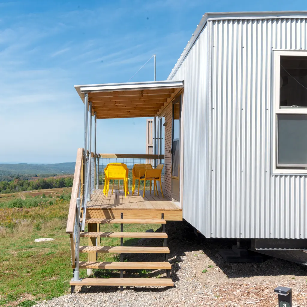 A compact prefabricated home with metal siding, a raised porch and steps.