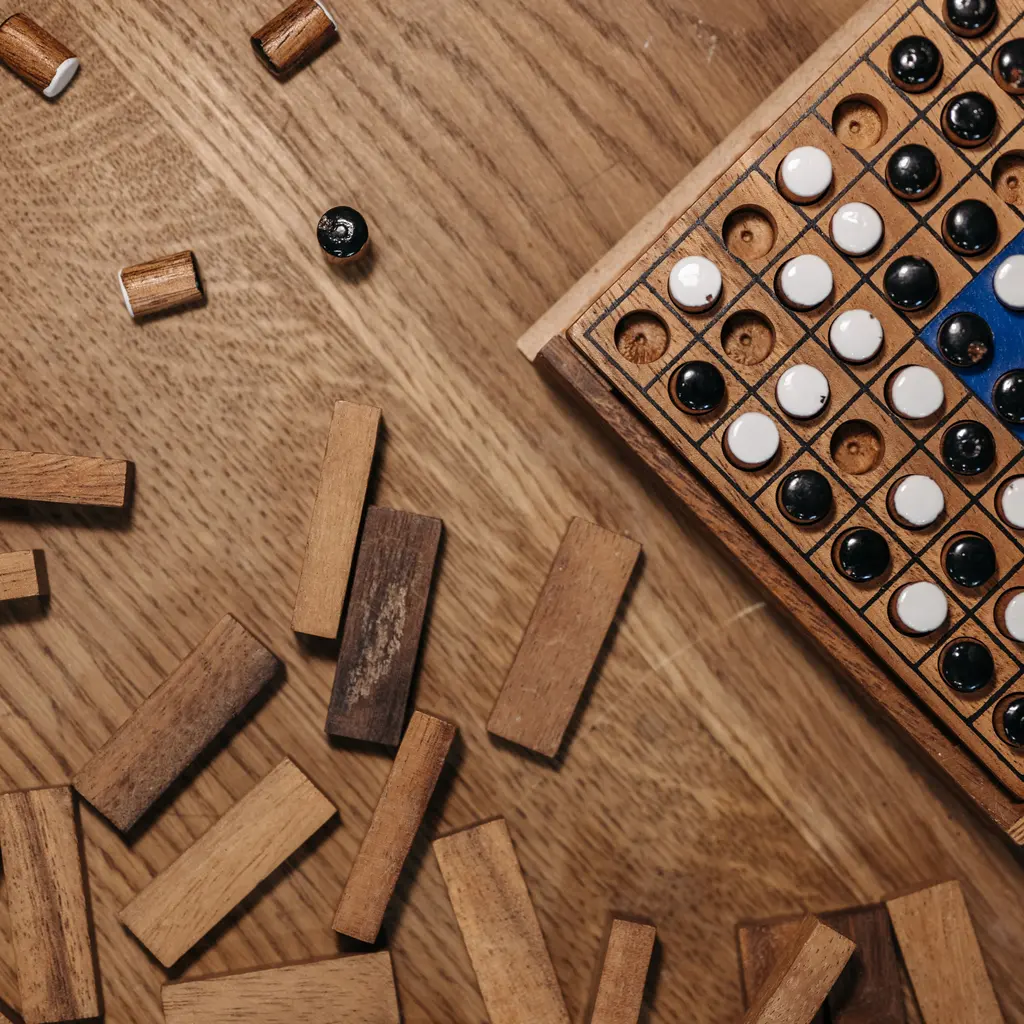 Wooden game blocks and black-and-white playing pieces arranged on a wooden board.