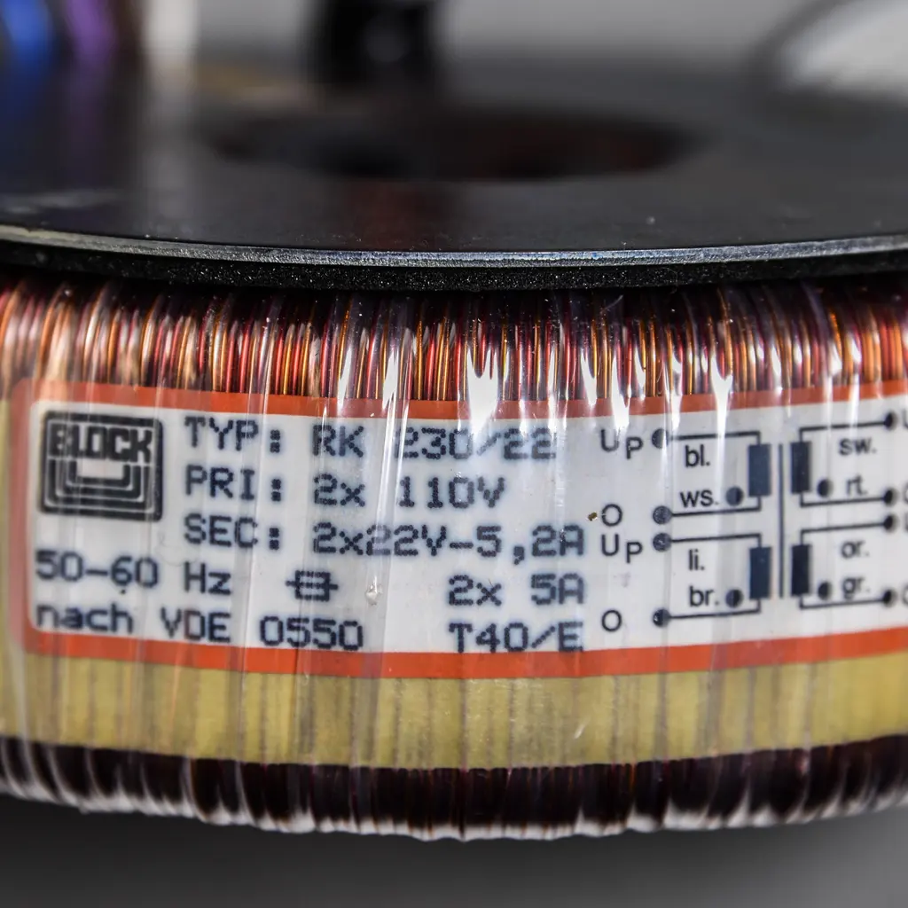 Close-up of copper windings and electrical ratings on a toroidal power transformer.