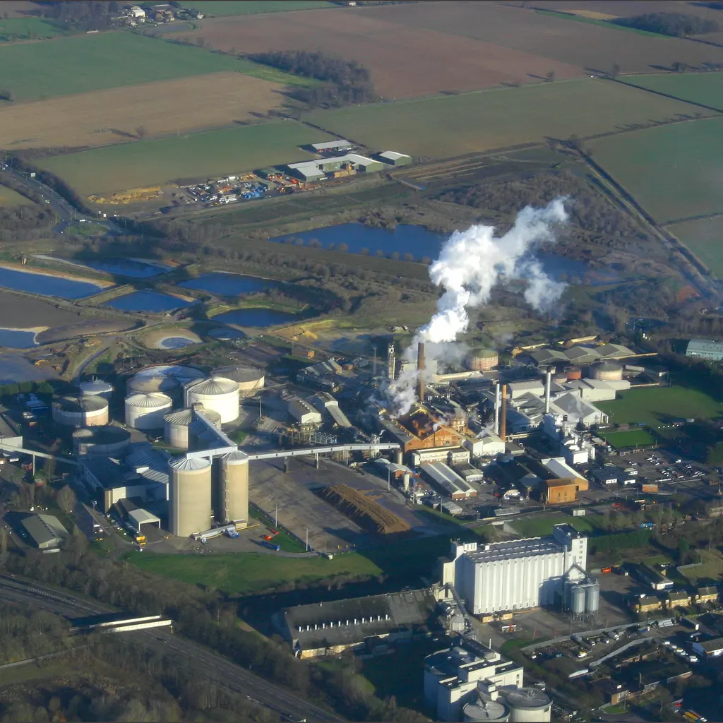 An aerial view of a beet-sugar factory with silos, processing buildings and vapor rising above the site.