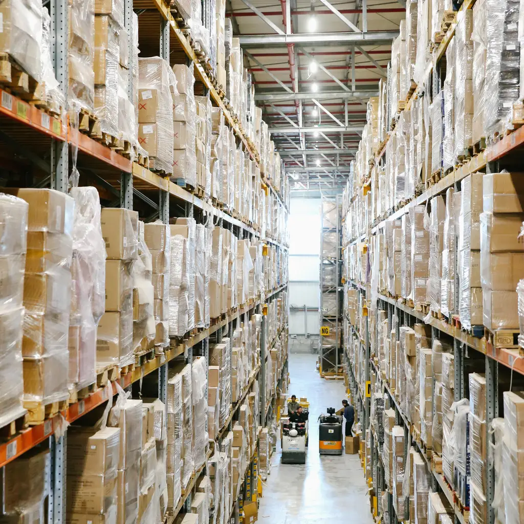 Stocked pallets and cartons along a high-bay warehouse aisle.