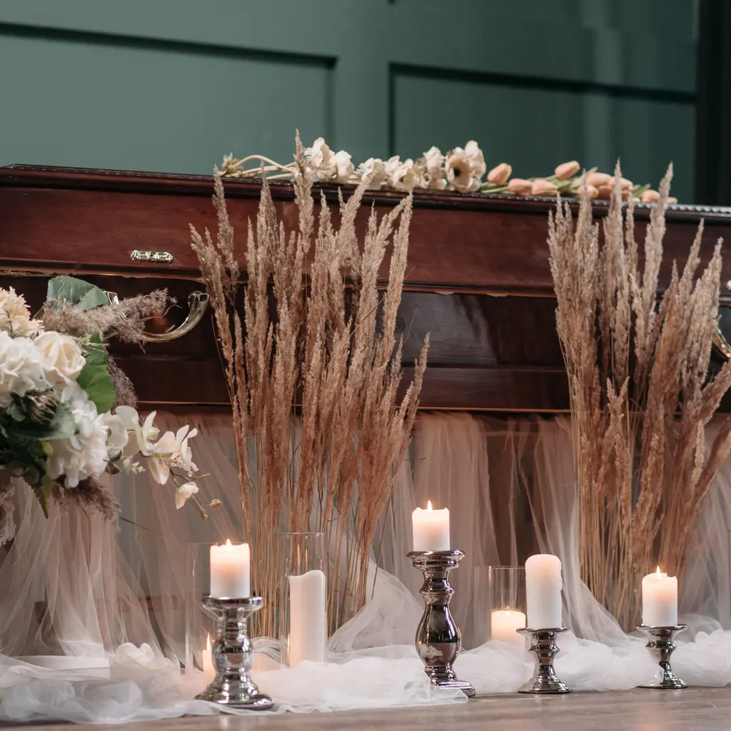 A polished wooden casket with flowers and candles arranged nearby.