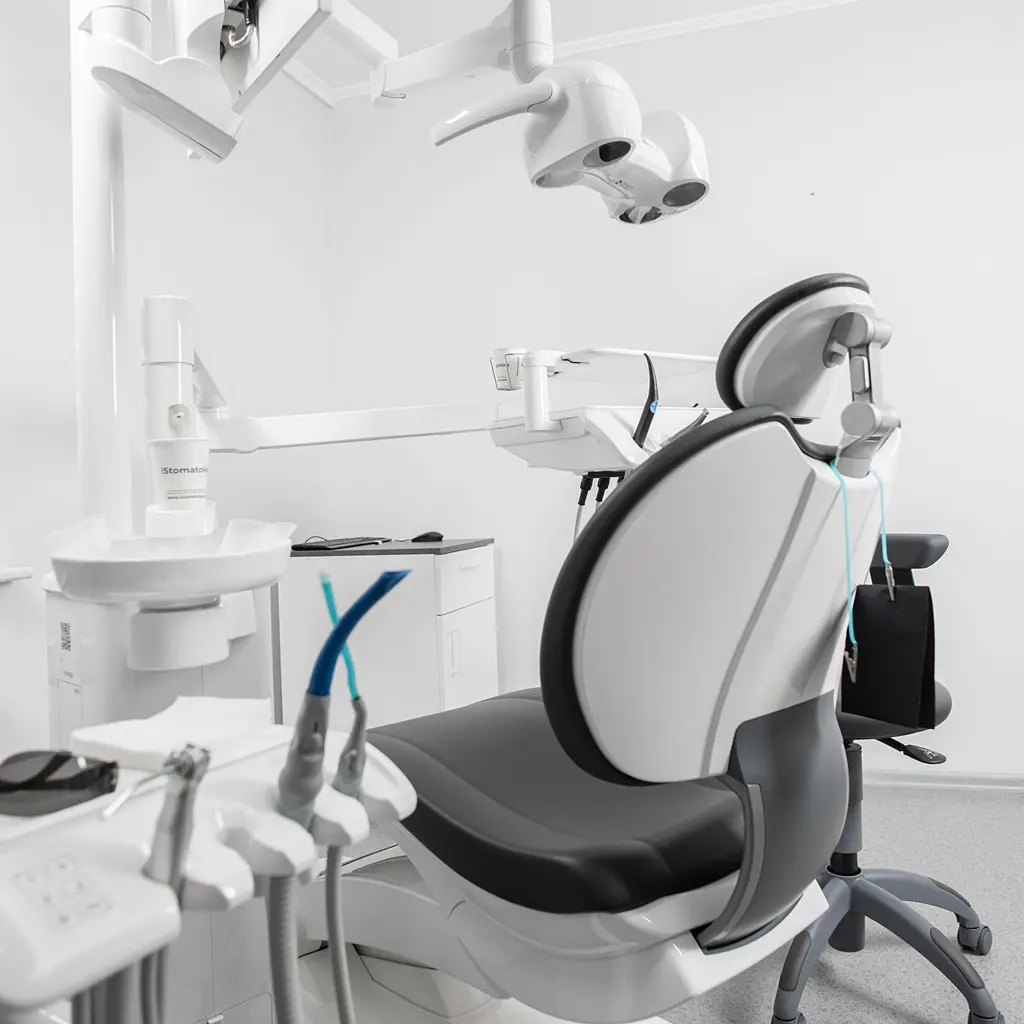 A dental treatment chair with an overhead light and adjacent dental equipment.