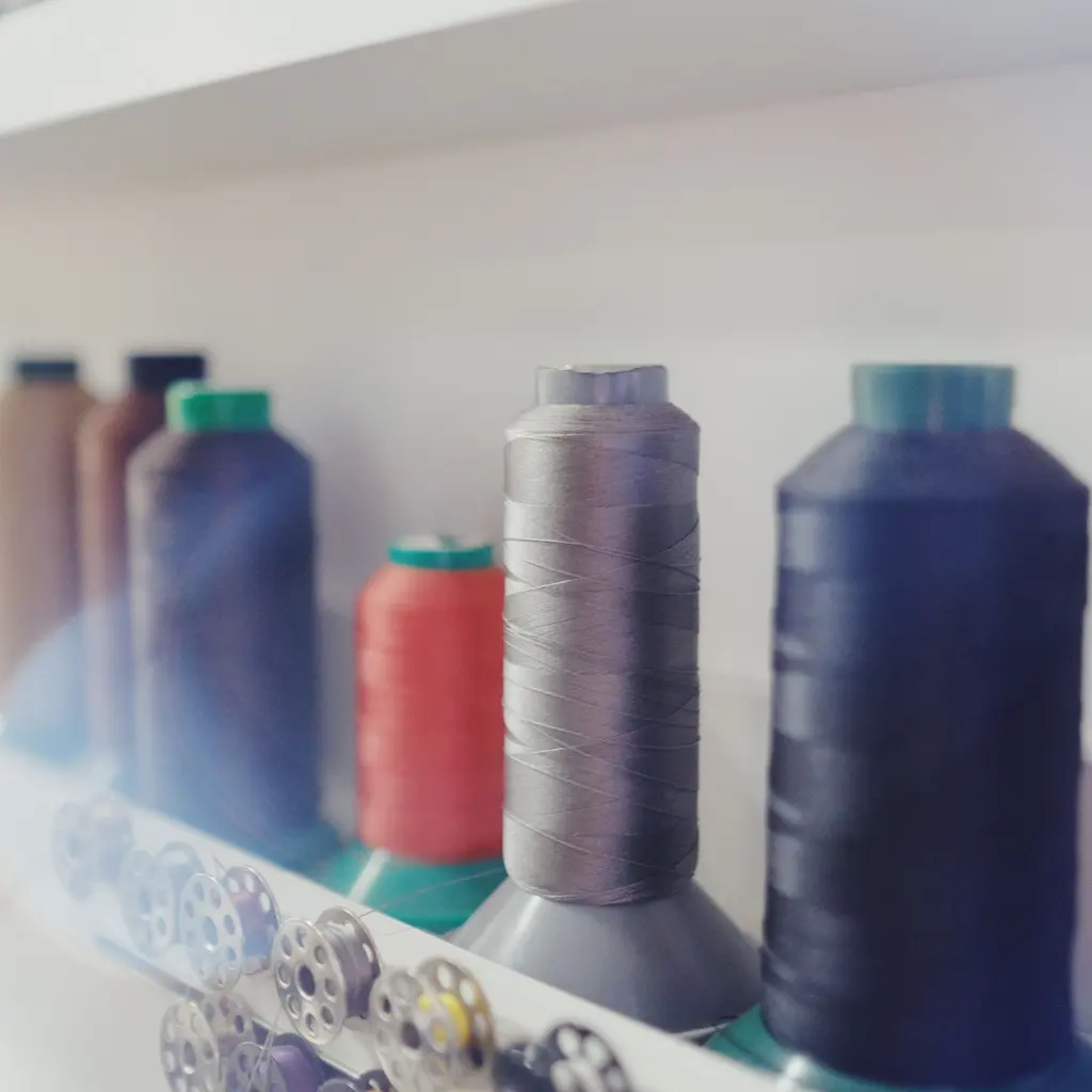 Large spools of sewing thread and metal bobbins arranged on shelving.