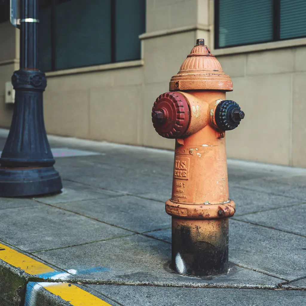 An orange fire hydrant installed beside a paved sidewalk.