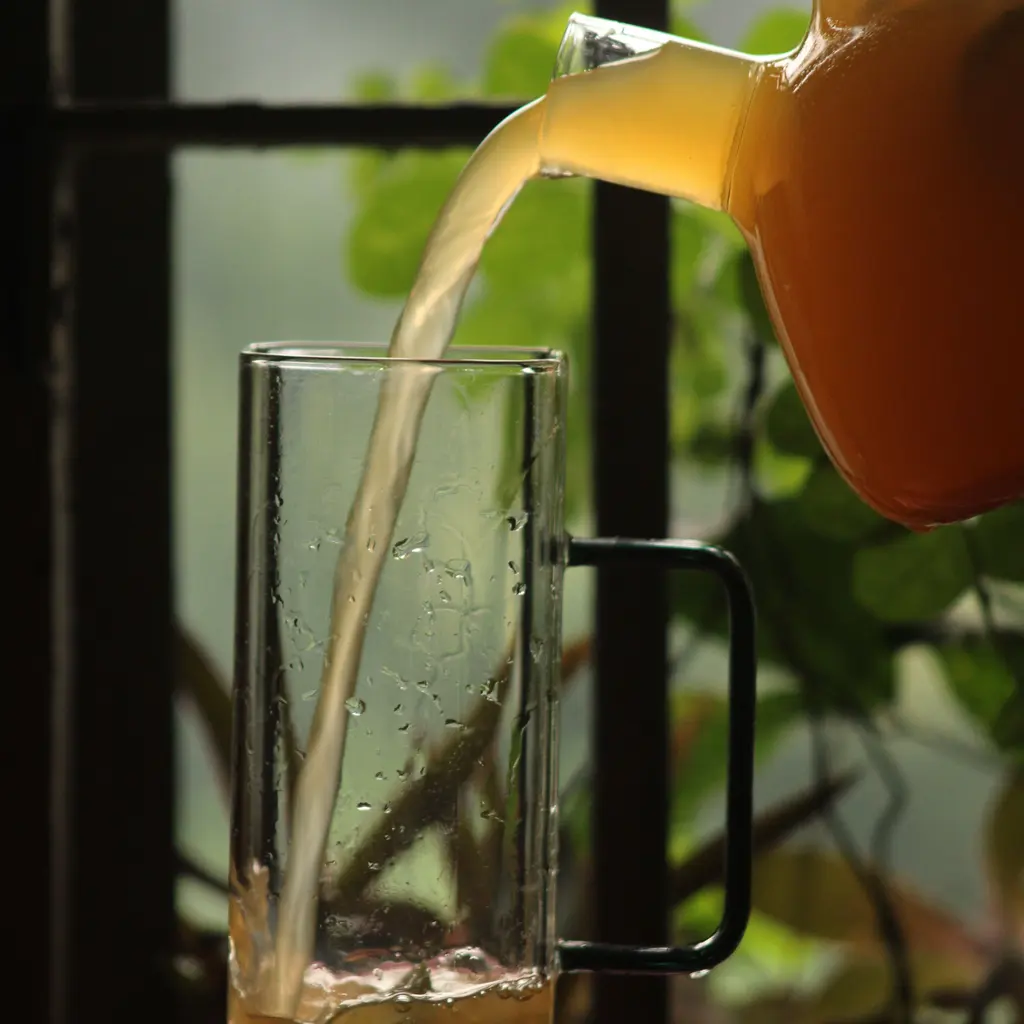 Orange juice pouring from a pitcher into a clear glass.