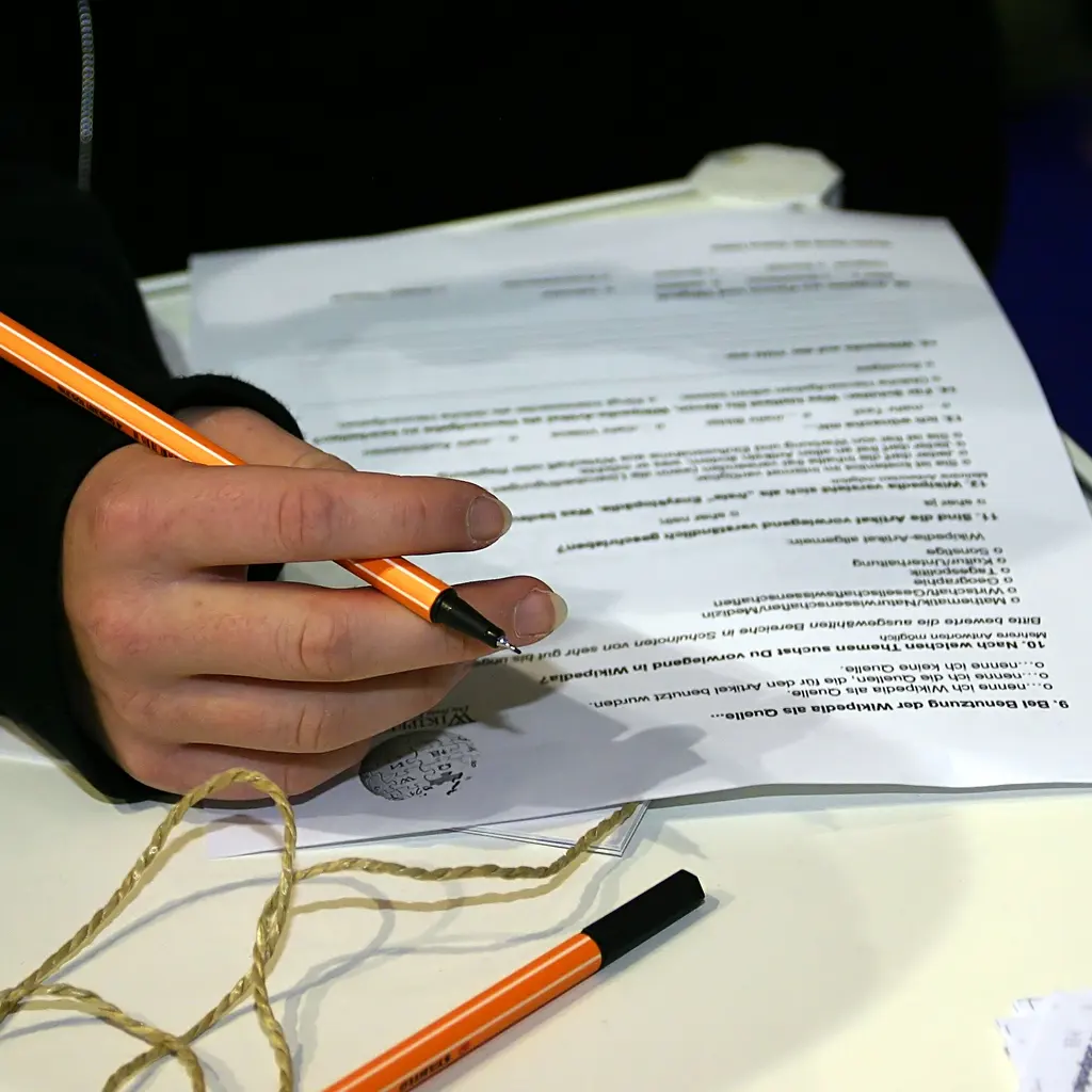 A person completing a printed questionnaire with a pencil.