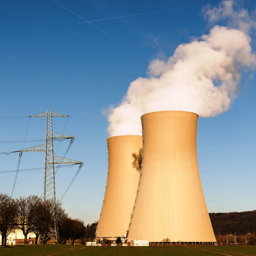 Cooling towers releasing vapor beside transmission lines.