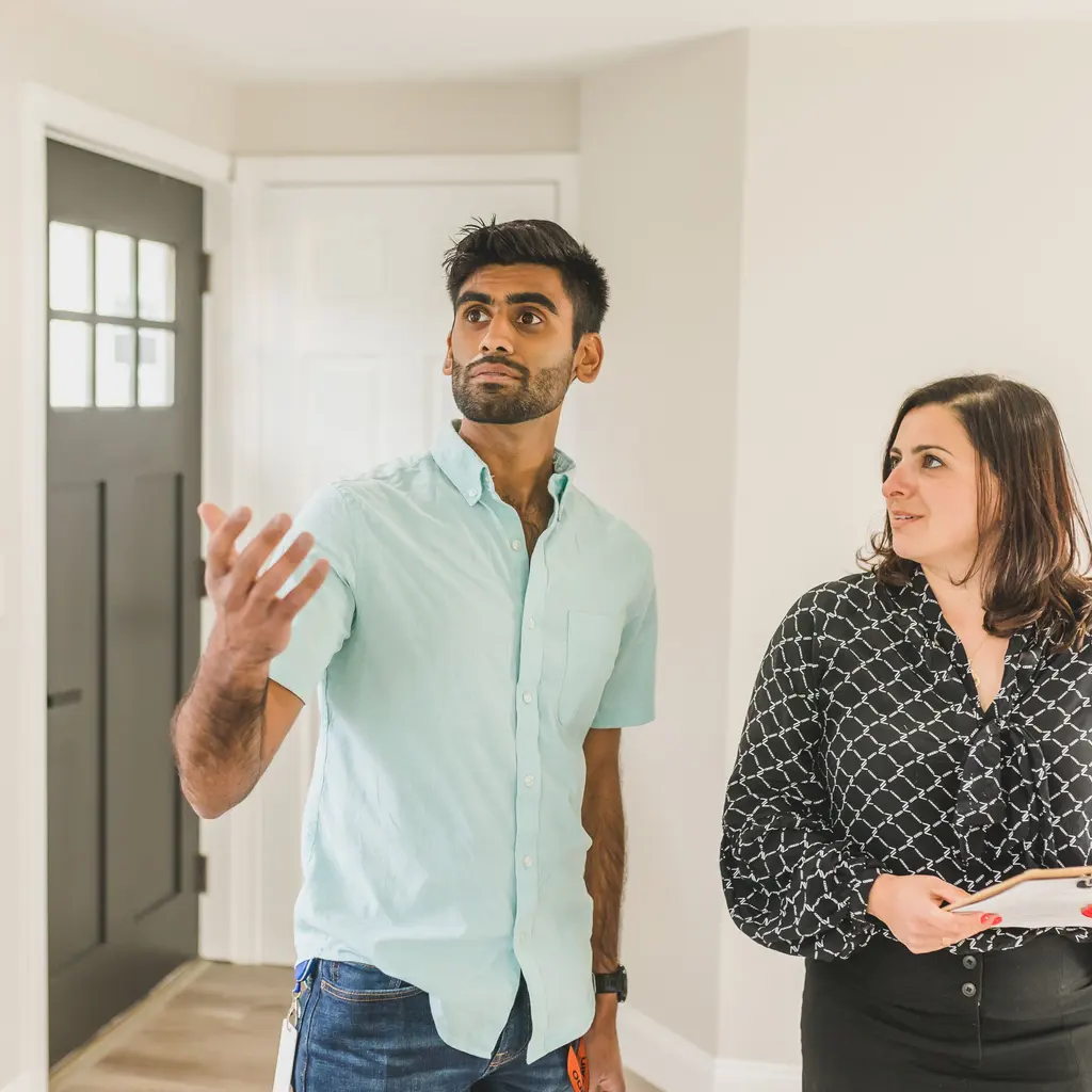 A real estate professional discussing an empty home’s interior with a visitor.