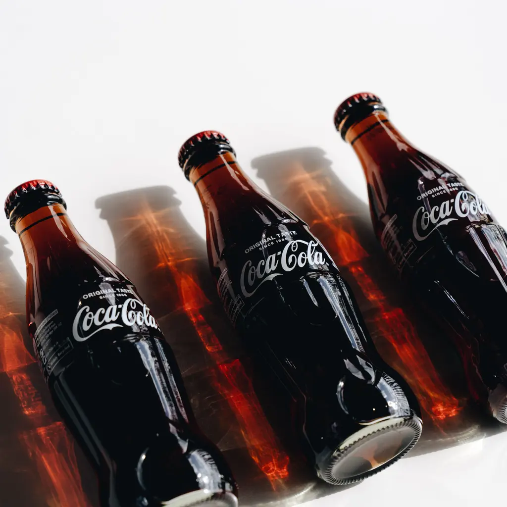 Capped glass cola bottles arranged in sunlight.