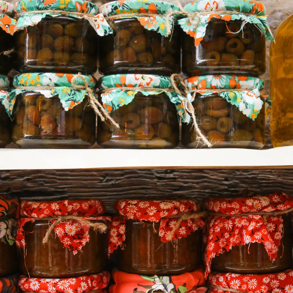Sealed glass jars of preserved vegetables arranged on shelves.