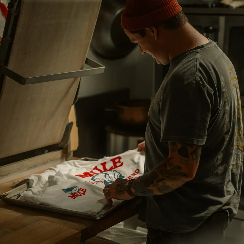 A worker finishing a printed T-shirt at a workshop heat press.