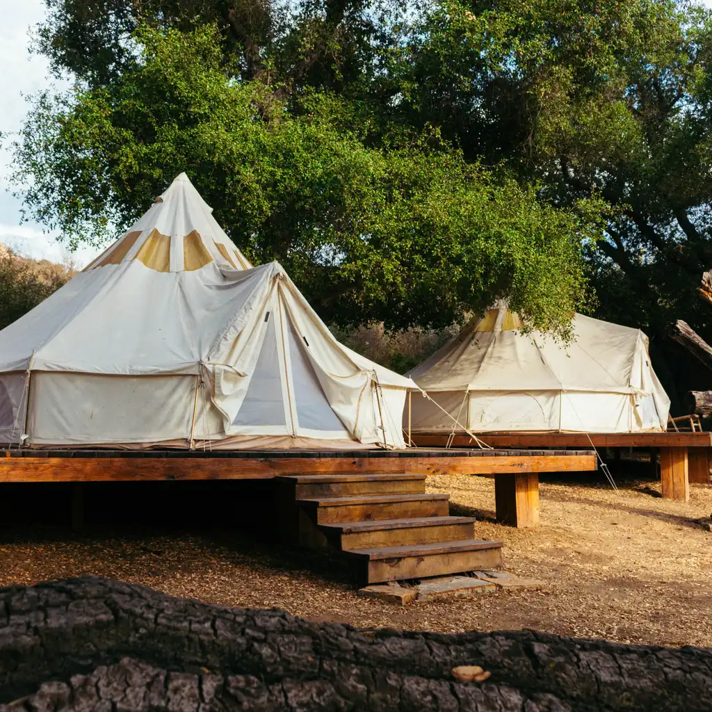 Canvas bell tents standing on raised wooden platforms.