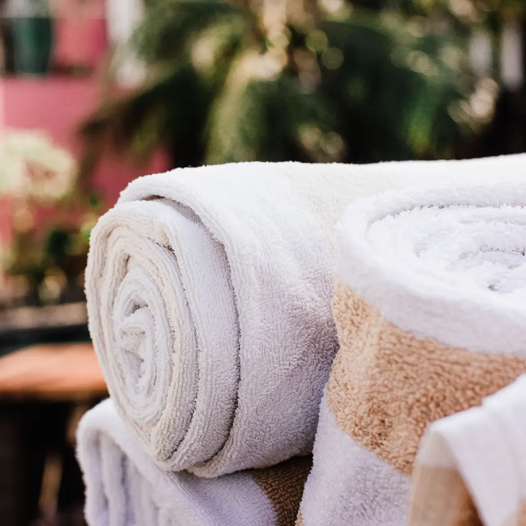Rolled cotton bath towels stacked together, showing their looped fabric texture.