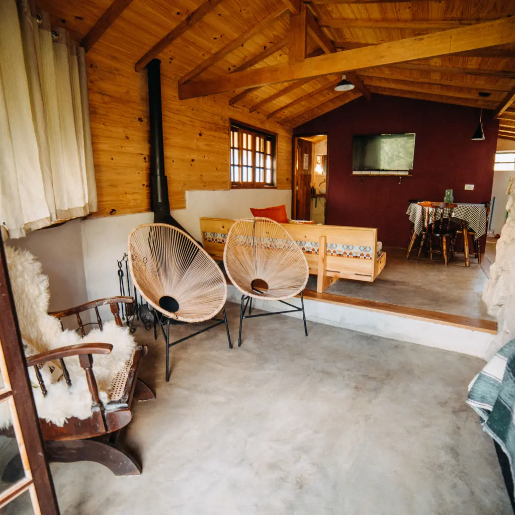 A furnished wooden cabin interior with chairs and a bed beyond a small step.