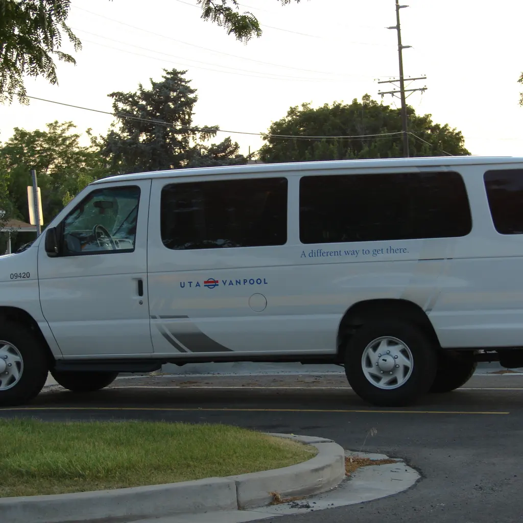 A white vanpool passenger van with route markings.