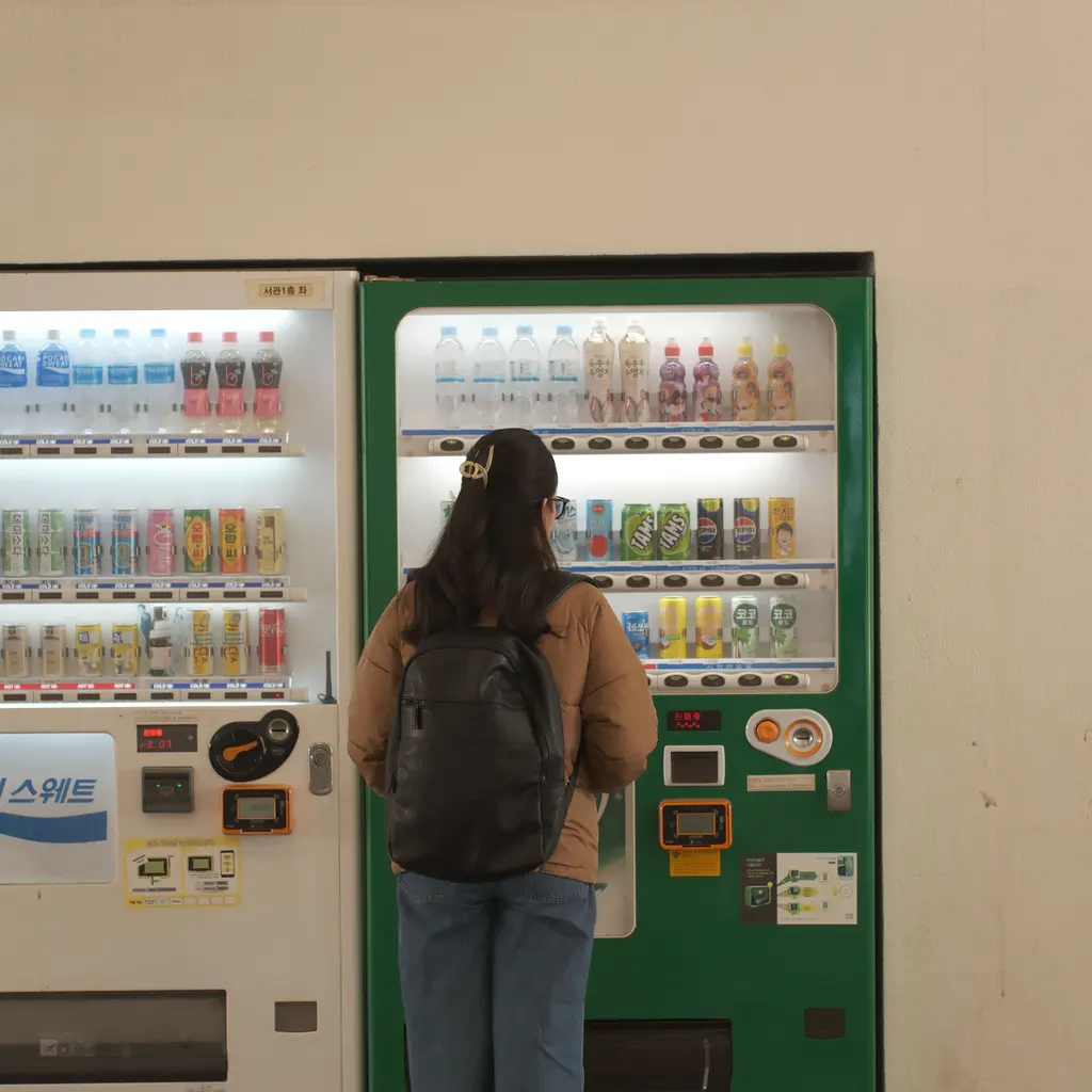 A customer choosing a drink from illuminated vending machines.