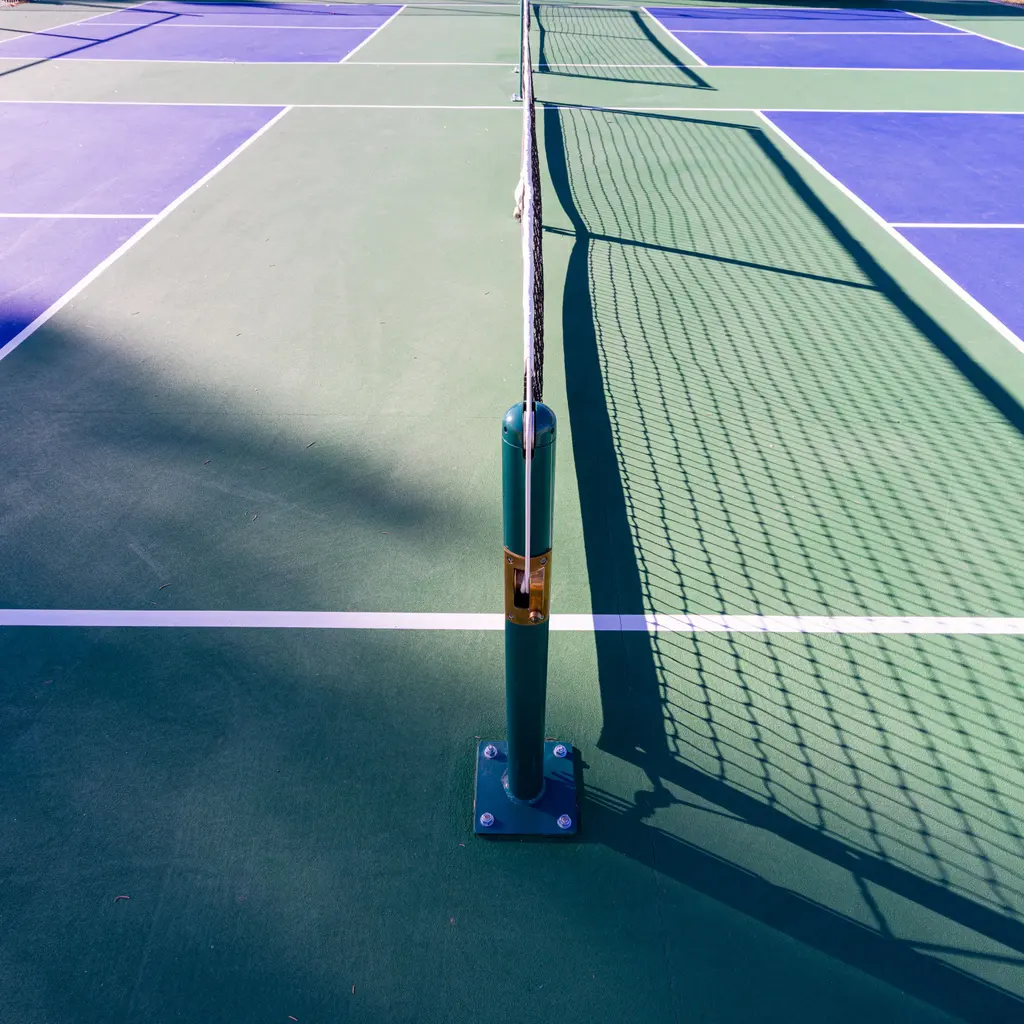 A net divides an empty blue-and-green pickleball court.