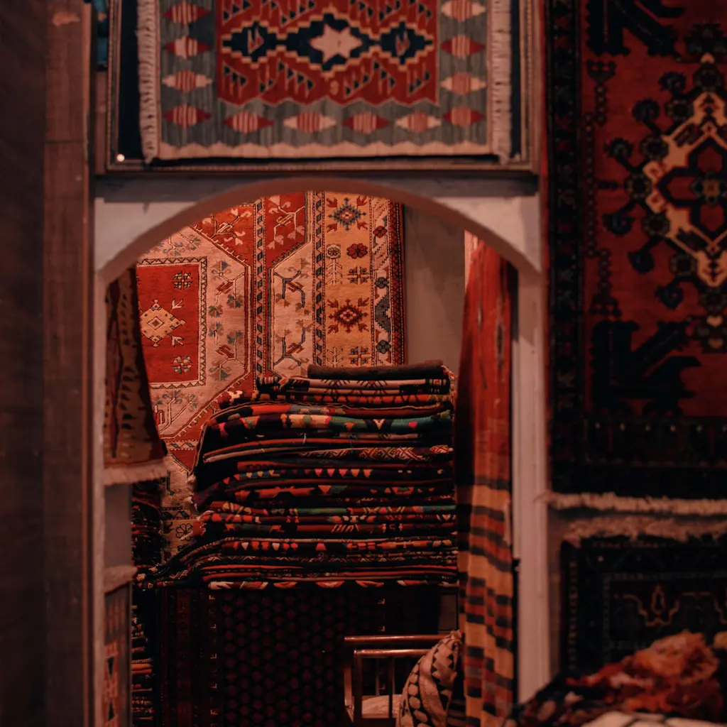 Patterned rugs hanging and stacked inside a carpet shop.
