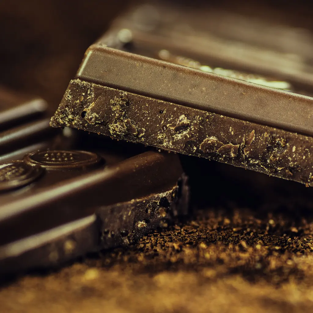 Stacked dark chocolate bars dusted with cocoa powder.