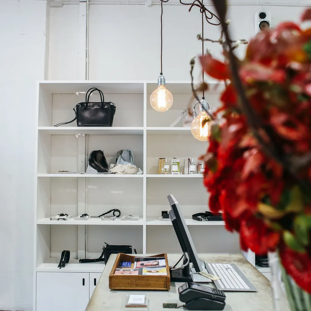 Built-in white retail display shelves holding handbags and small merchandise.