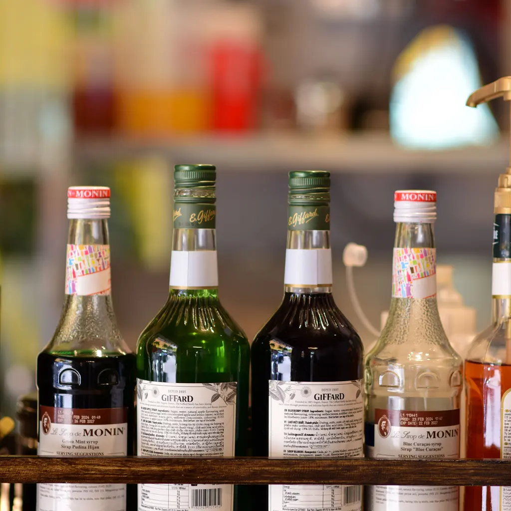 Bottles of flavored syrups arranged on a shelf.