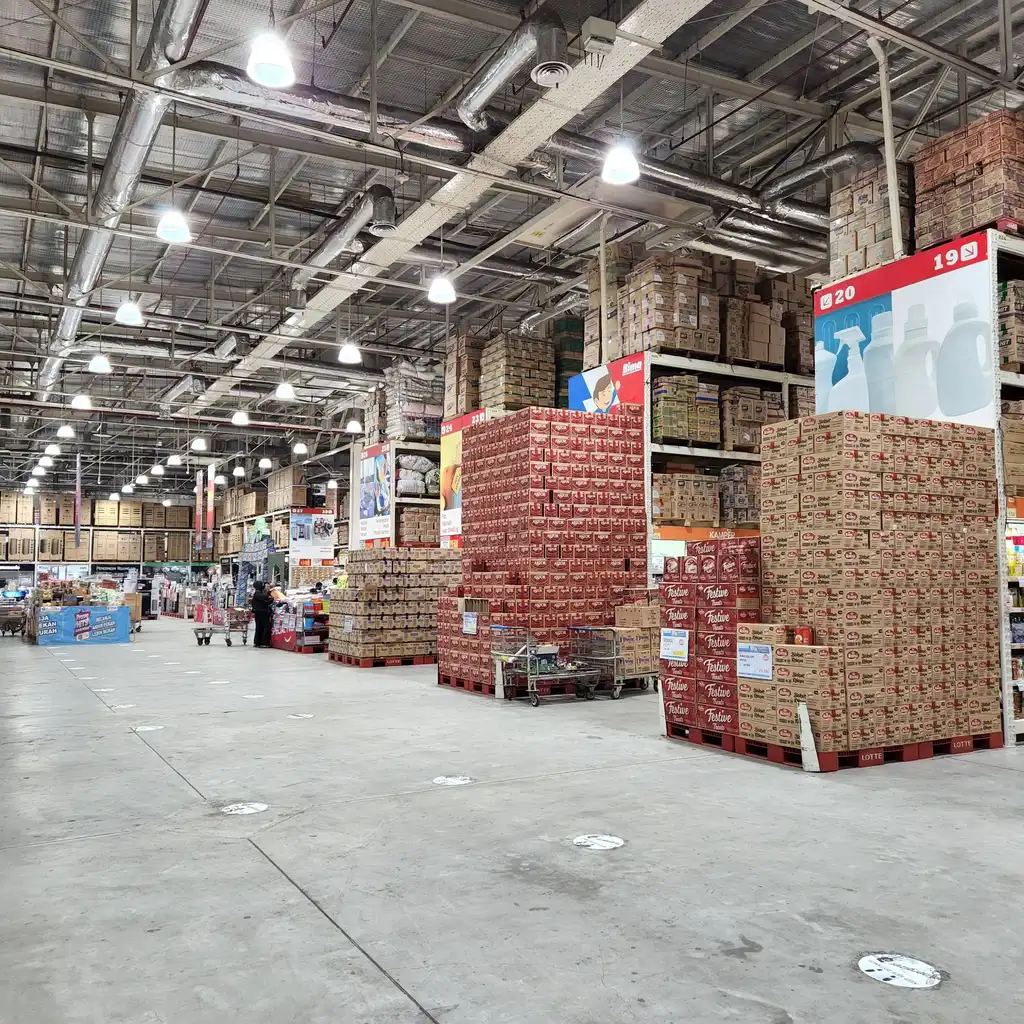 Tall stacks of boxed bulk goods beside a wide aisle in a warehouse-style store.