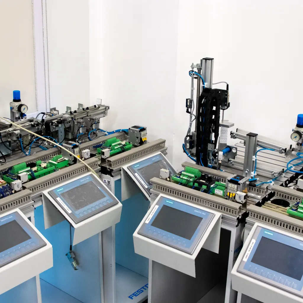 Industrial automation stations with touch-screen control panels and wired machine assemblies.