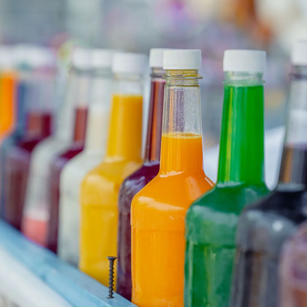 Rows of capped bottles containing brightly colored non-alcoholic drinks.