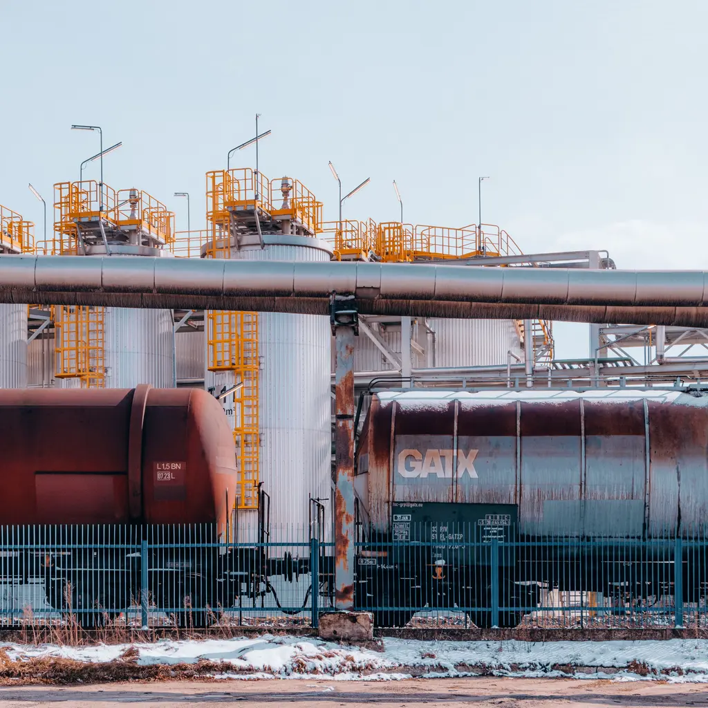 Railway tank cars standing beside industrial pipework.