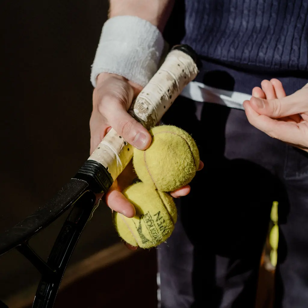 A tennis racket and yellow tennis balls held together in a close-up view.