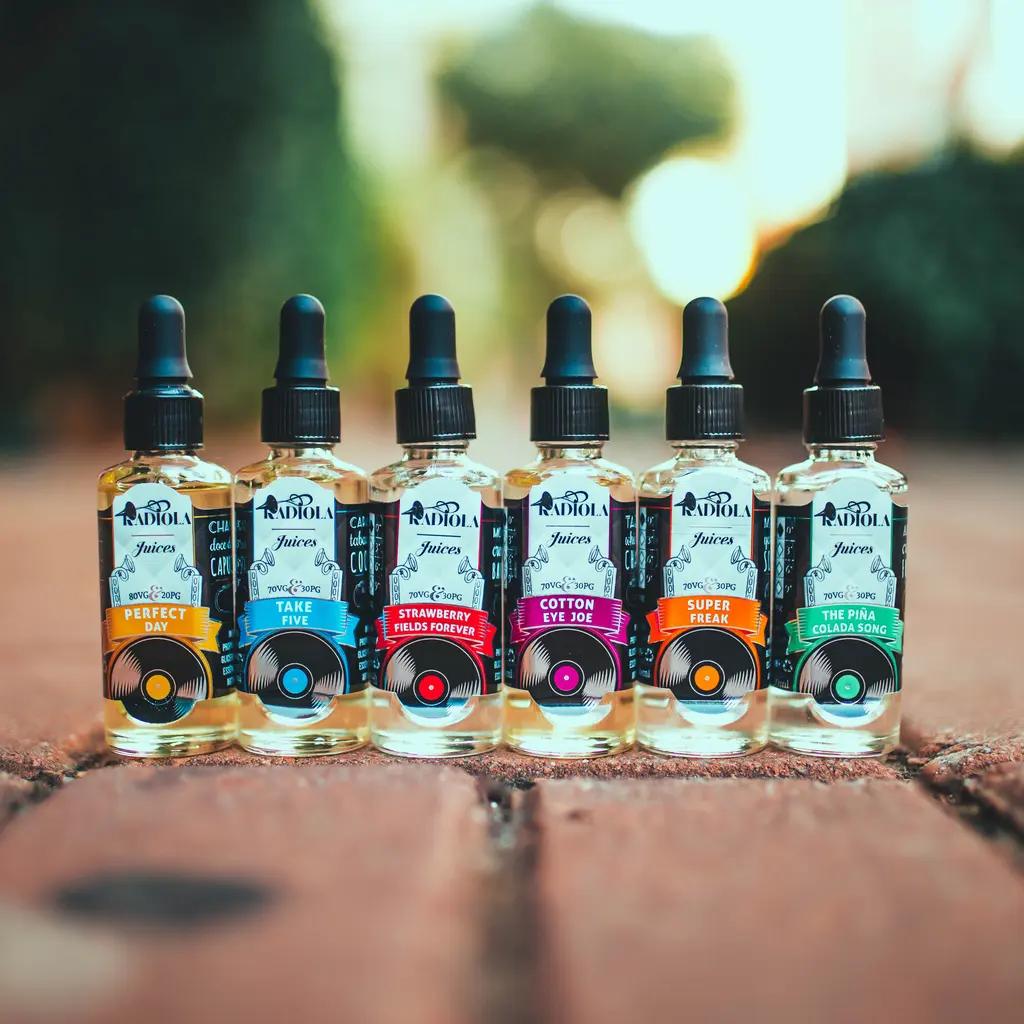 Glass dropper bottles of e-cigarette liquid arranged in a row on a brick surface.