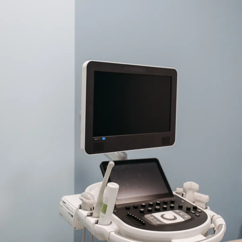 An ultrasound system with a blank screen, control panel and probe holders.