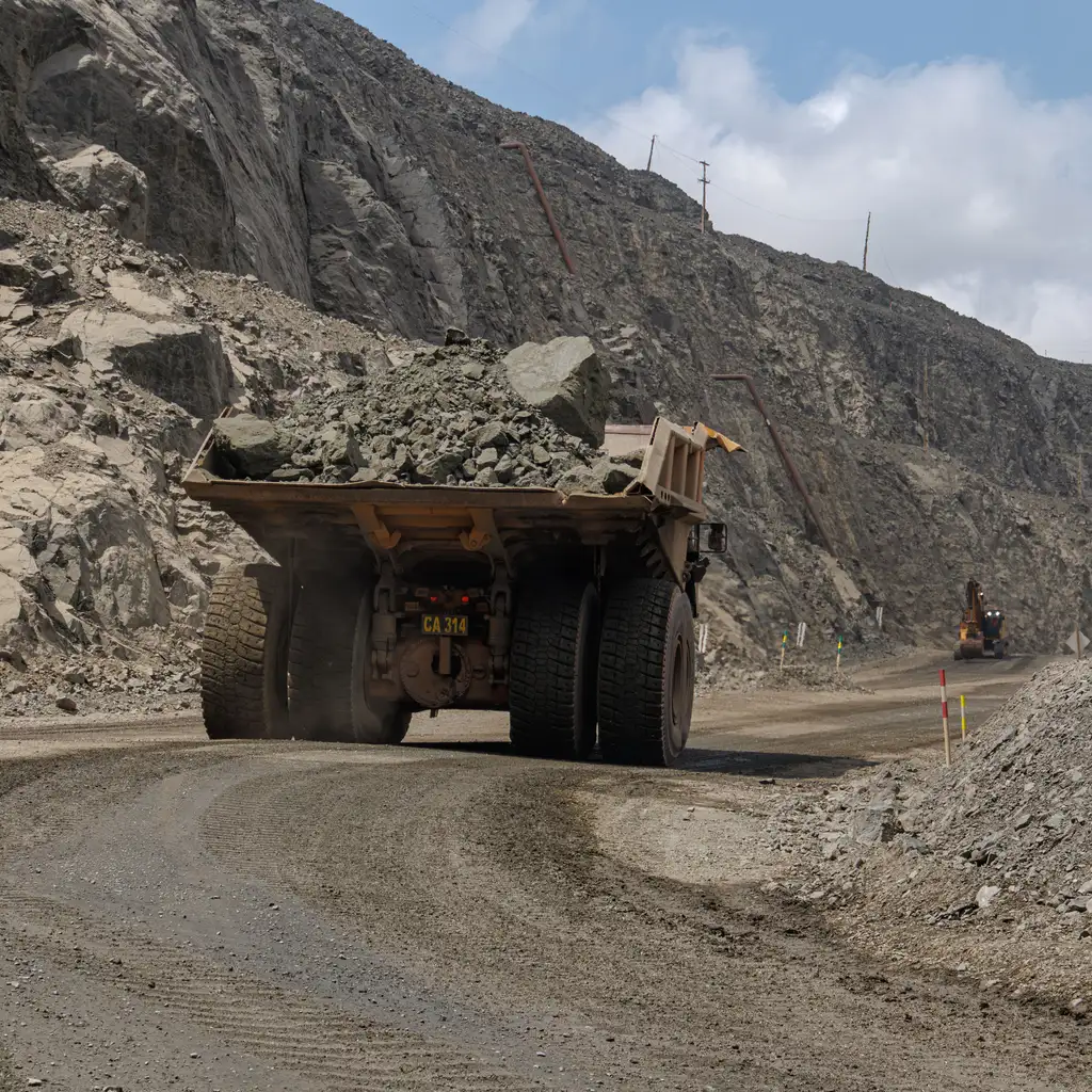 A large off-highway mining haul truck carrying rock through an open quarry.
